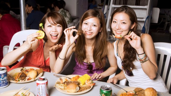 Three women eating delicious BBQ and enjoying beer on the Big Sunset Cruise in Tumon, Guam