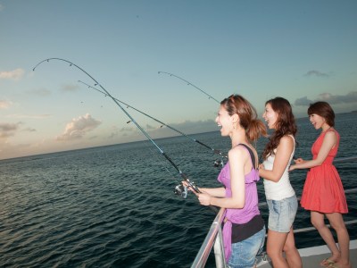 Three women fishing on the edge of the Big Sunset Cruise in Tumon, Guam