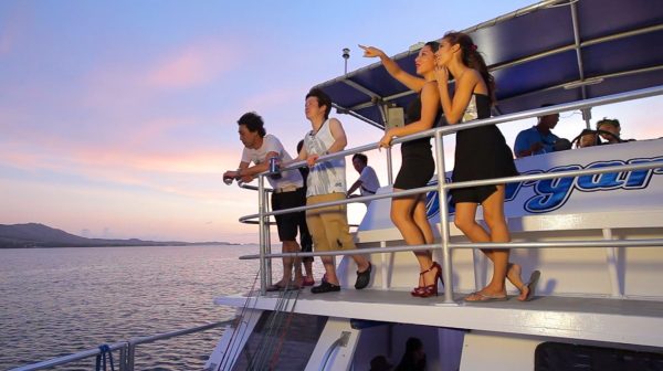 People standing on the deck of the boat on the Big Sunset Cruise as the sun set in Tumon, Guam