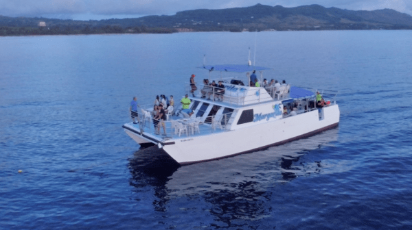 An aerial shot of the Big Sunset Cruise with people parting on the deck of the boat in Tumon, Guam