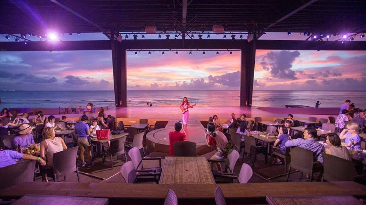 The sunset over the ocean as a performer plays the guitar at the Beach Bar & Grill in Tumon, Guam