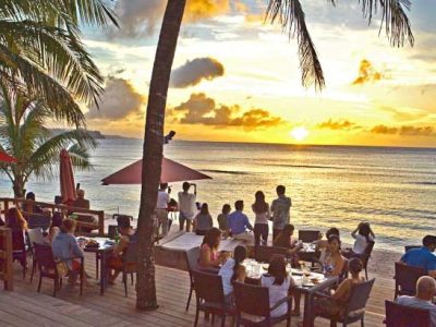 The sun setting over the ocean in Guam as onlookers enjoy a great dinner beachside at the Beach Bar & Grill in Tumon, Guam