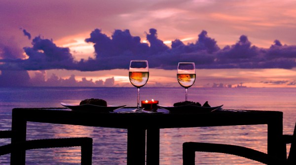 a table with two wine glasses and a candle lit as the sun sets in the distance in Tumon, Guam