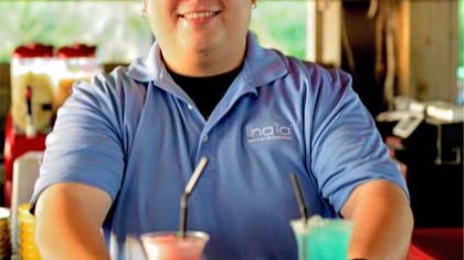 A bartender serving two cocktails in tall glasses