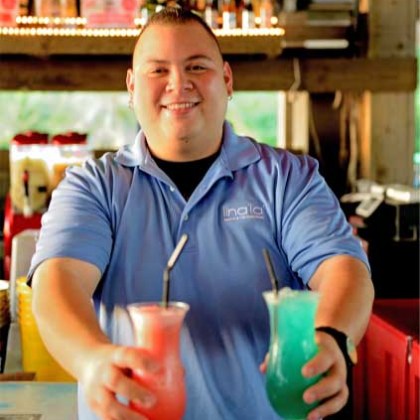 A bartender serving two cocktails in tall glasses