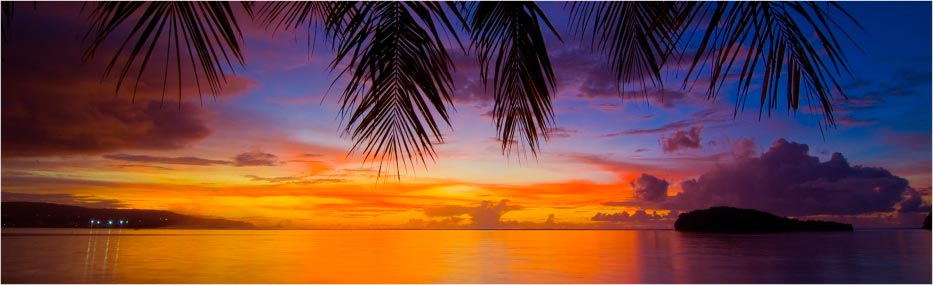 sightseeing-banner The sun setting over the ocean in Guam with the palm trees and clouds lighting being lit up