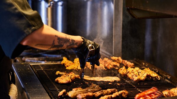 a person cooking hot dogs on a grill