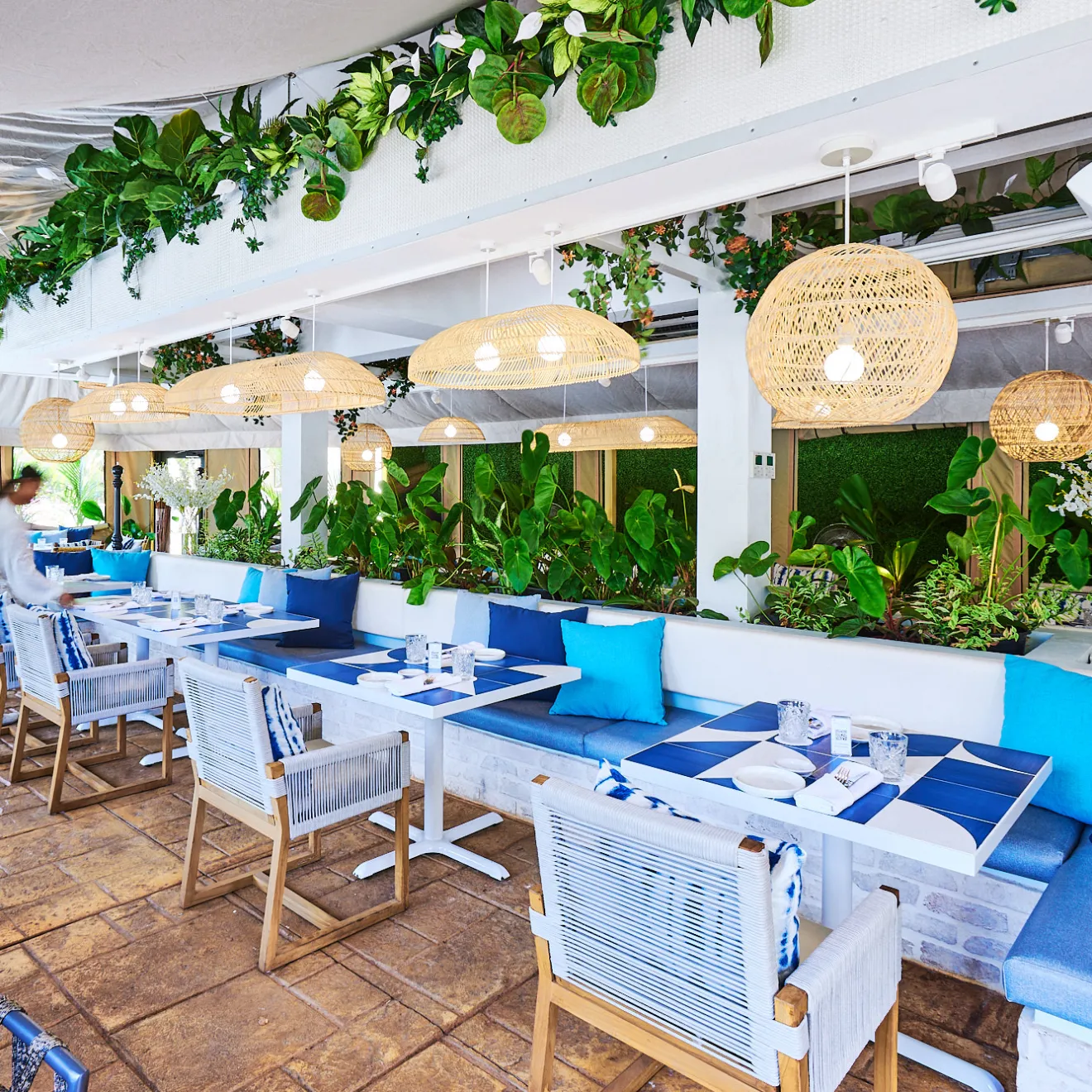 a group of people sitting at a table with a blue umbrella