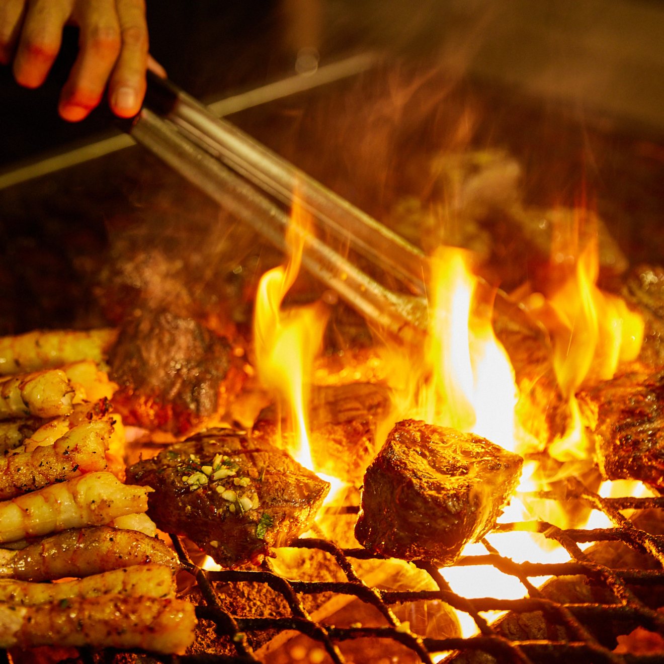 a person cooking hot dogs on a grill