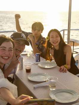 a woman sitting at a table with people in the water