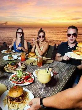 a group of people sitting at a table with food and water