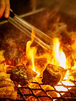 a person cooking hot dogs on a grill