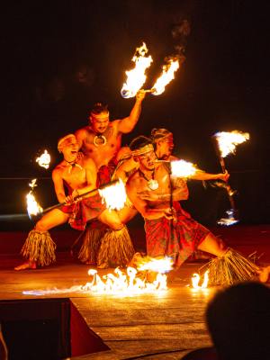 Four performers in traditional attire doing a fire dance at night.