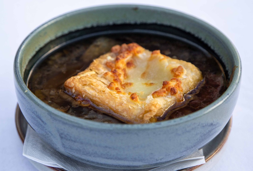 Bowl of soup topped with a piece of cheese-covered bread.