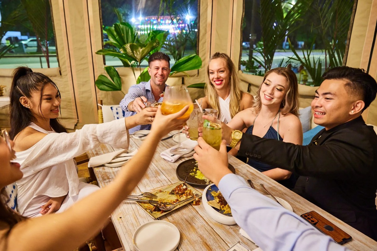 Elizabeth Debicki et al. sitting at a table posing for the camera