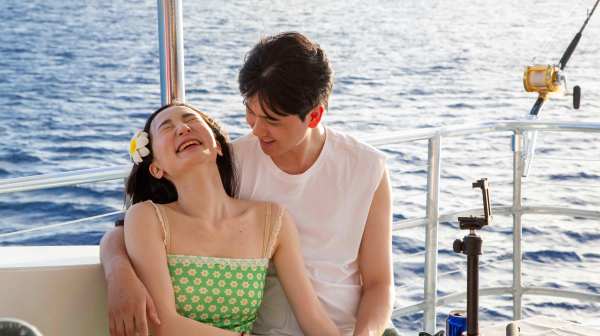 a man and woman sitting next to a body of water