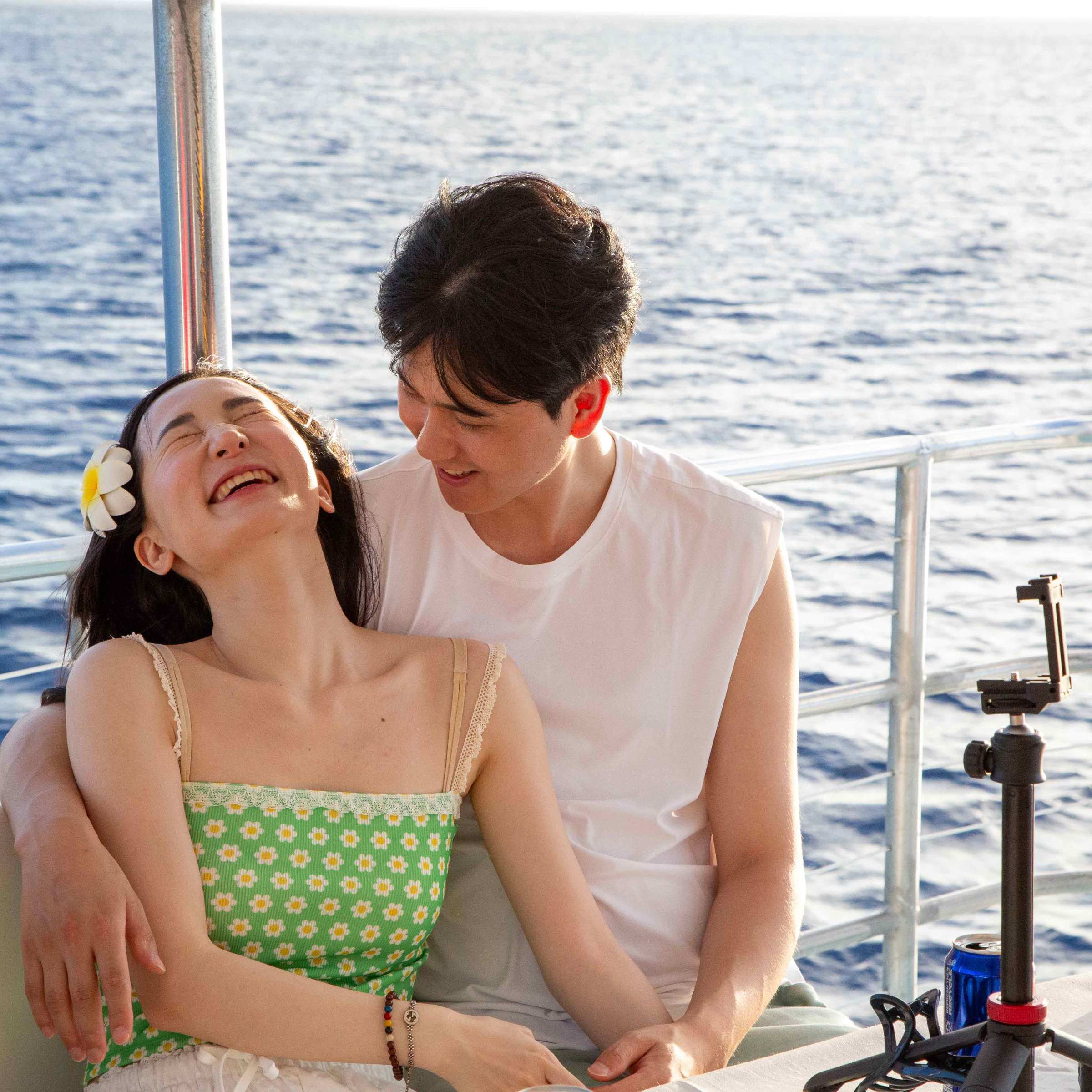 a man and woman sitting next to a body of water