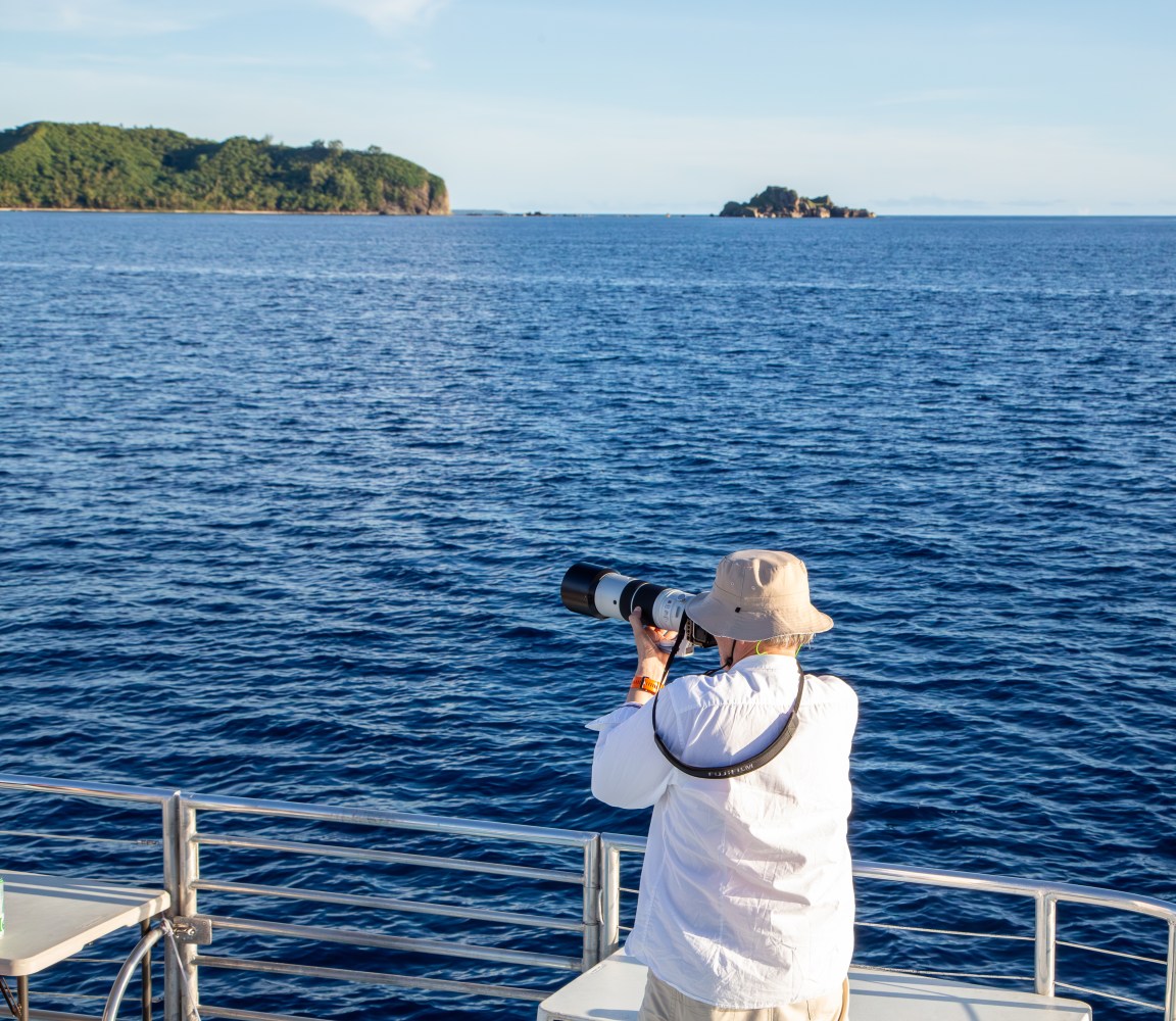 Person photographing ocean view with islands in the distance.