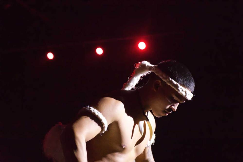 Man with white headband and armbands performing under stage lights.