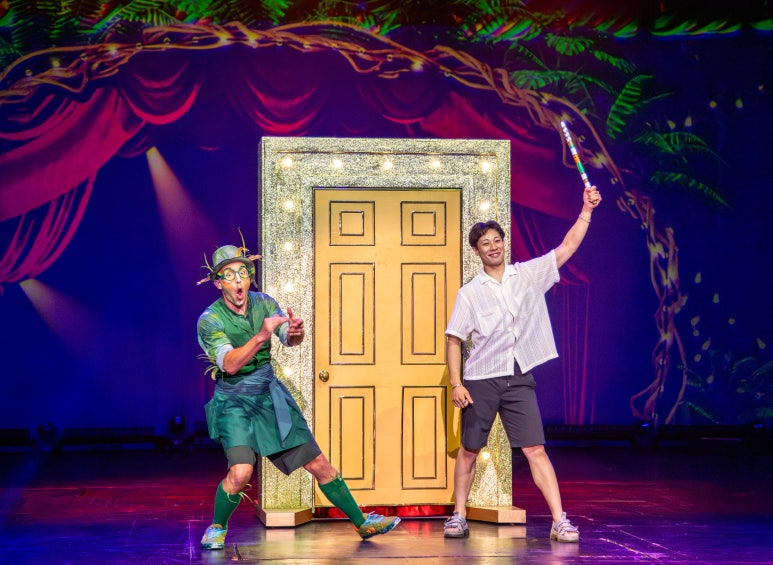 Two performers on stage with a sparkling door, one holding a toothbrush and the other in a green outfit.