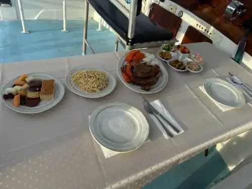 Table set for two with plates of food including pasta, fruit, and meat.