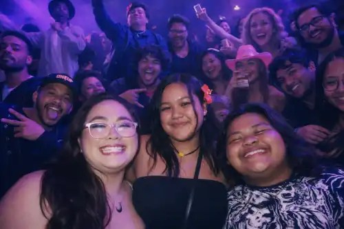 A group of smiling people in a dimly lit, vibrant party atmosphere.