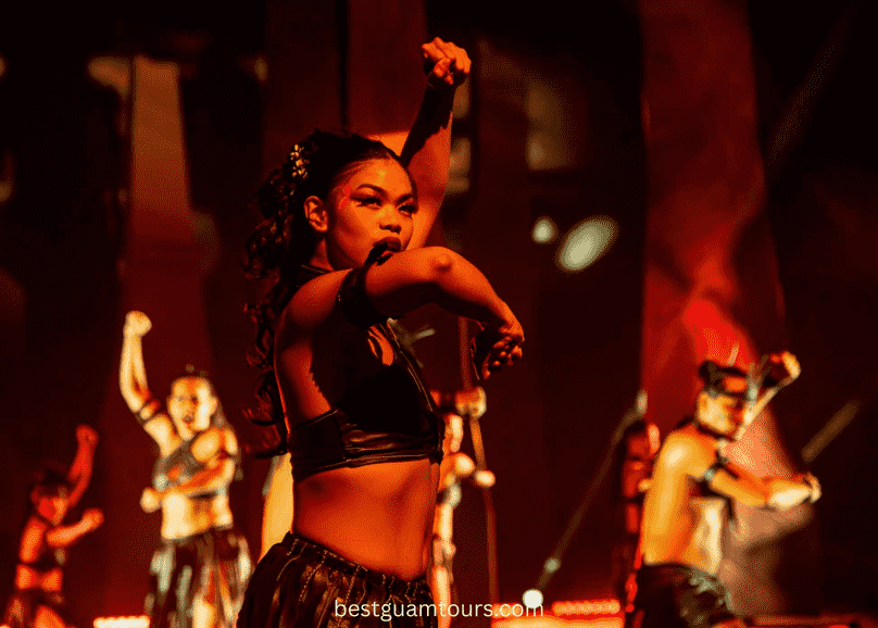 Dancers perform energetically under red lighting, wearing traditional costumes.