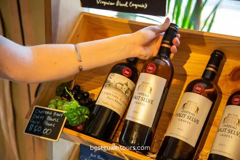 Person holding a wine bottle near a shelf with more wine bottles.