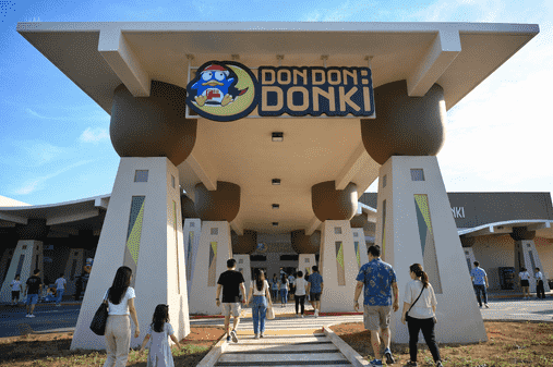 People entering a Don Don Donki store with a large sign above the entrance.