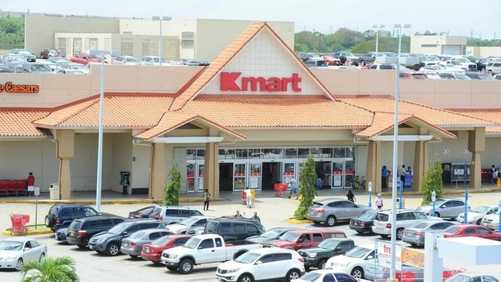 Kmart store with a parking lot full of cars and people entering the store.
