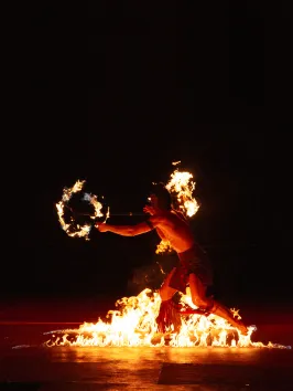 Person performing fire dance at night with flames around.