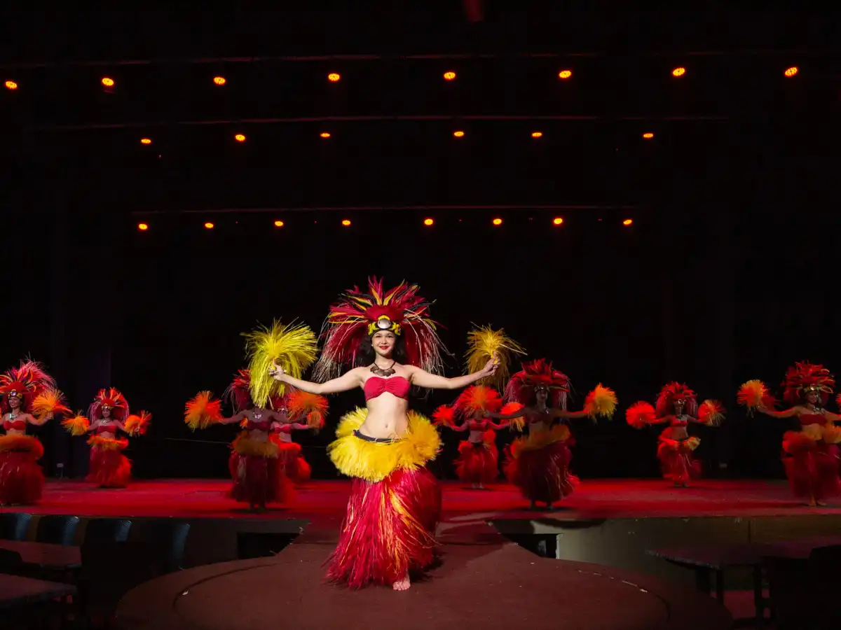 Dancers in vibrant costumes perform a traditional Polynesian dance on stage.