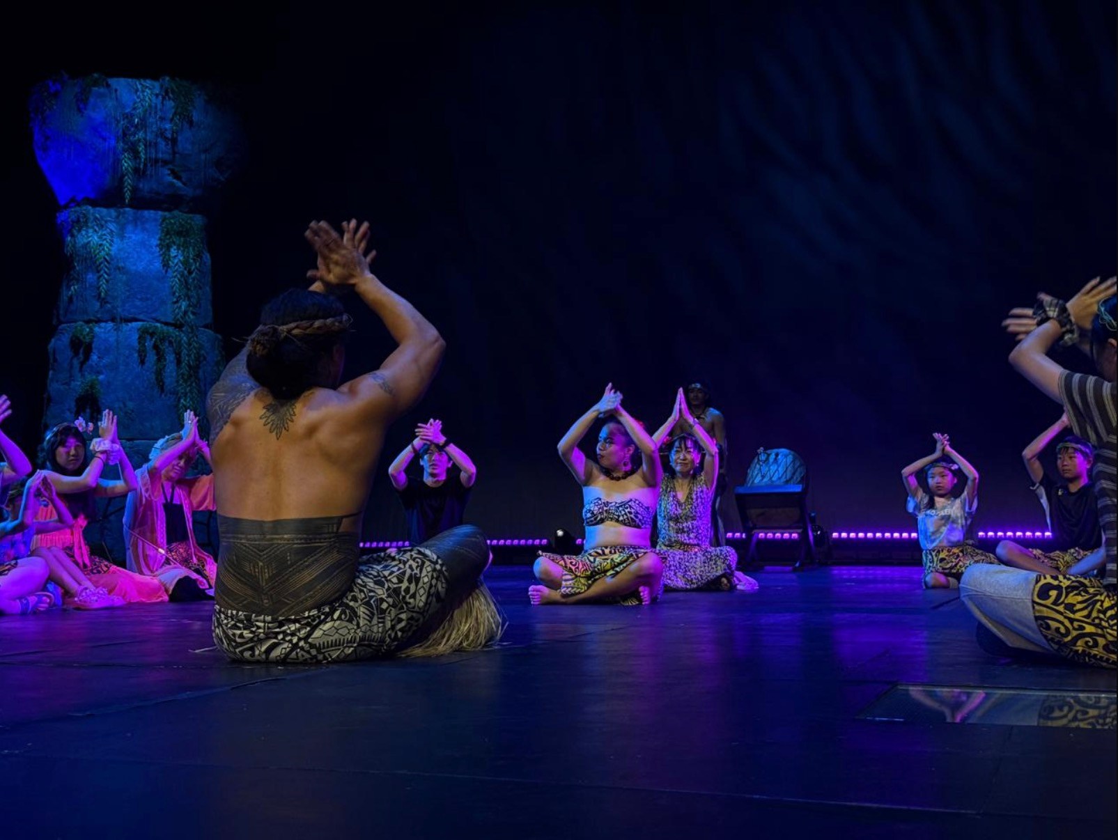 Group performing a traditional dance on stage with colorful costumes.