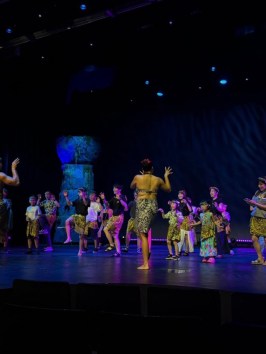 Performers in traditional attire dancing on a dimly lit stage.
