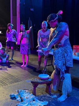 People in traditional attire on stage performing a cultural demonstration.